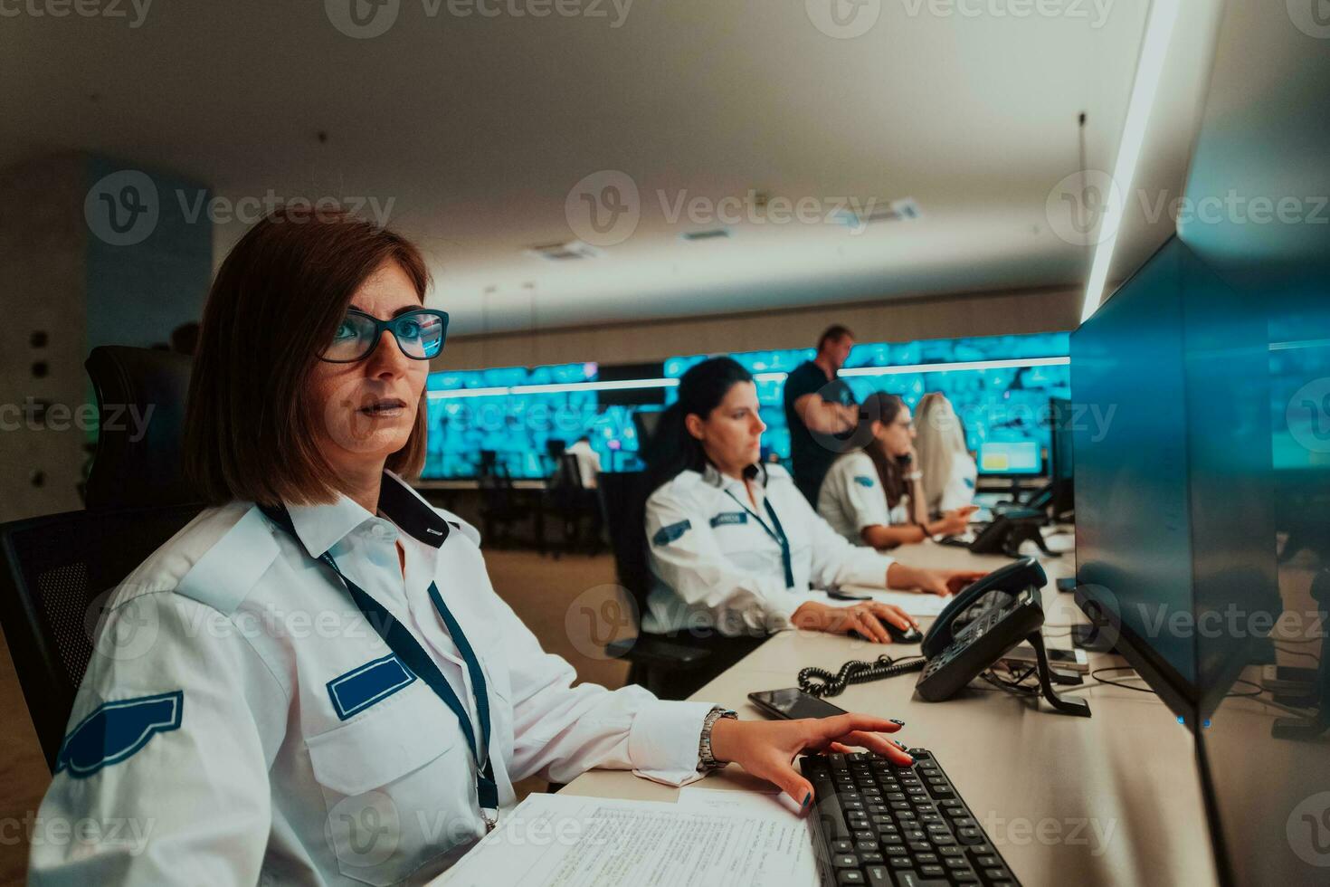 Group of female security operators working in a data system control room Technical Operators Working at workstation with multiple displays, security guards working on multiple monitors in surveillan photo
