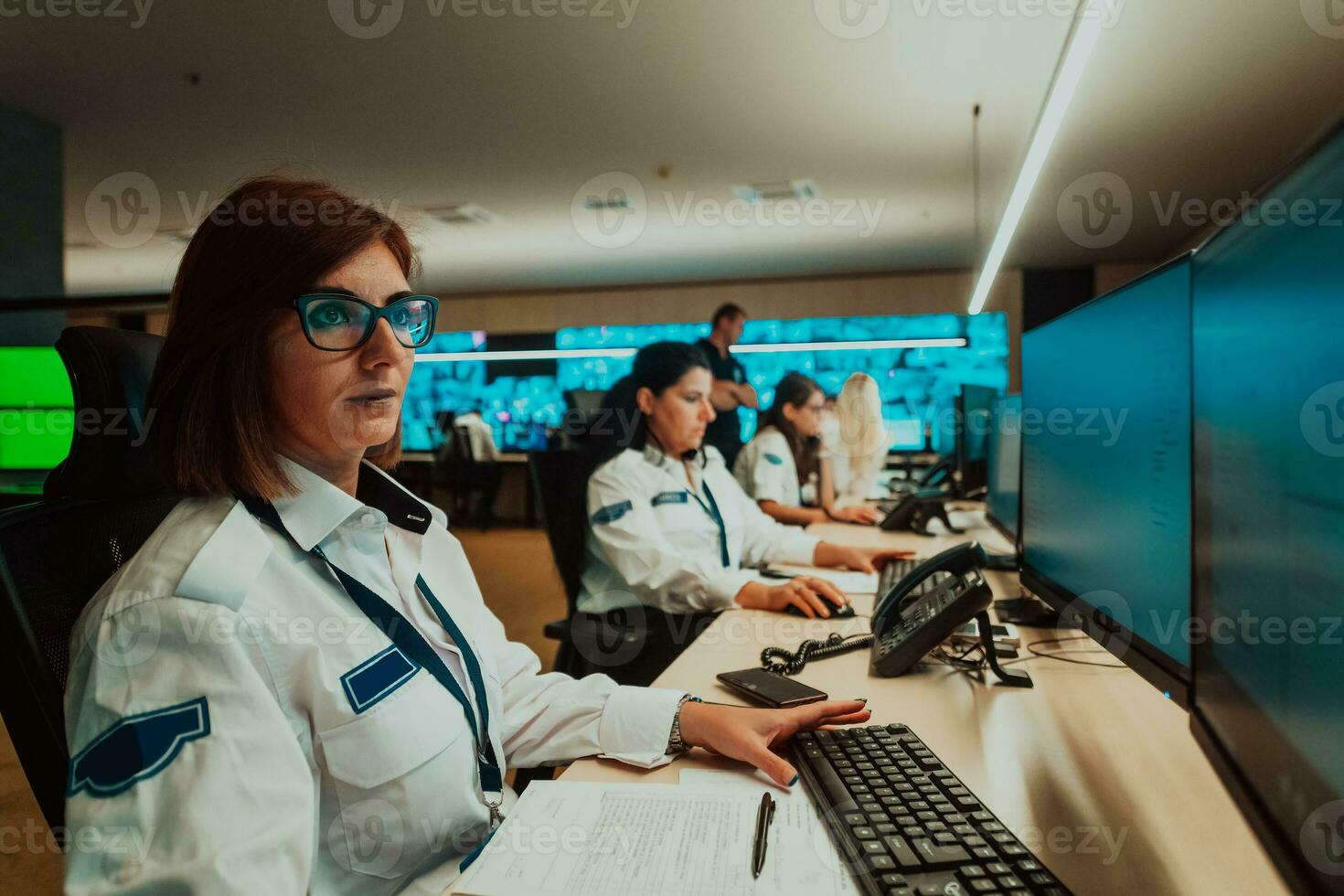 Group of female security operators working in a data system control room Technical Operators Working at workstation with multiple displays, security guards working on multiple monitors in surveillan photo