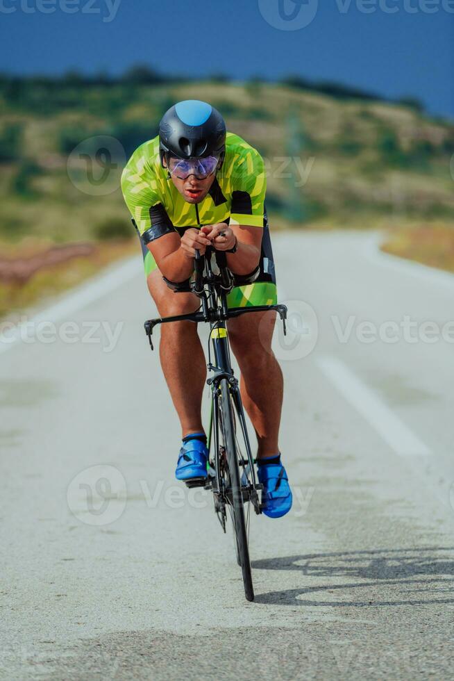 lleno longitud retrato de un activo triatleta en ropa de deporte y con un protector casco montando un bicicleta. selectivo atención foto