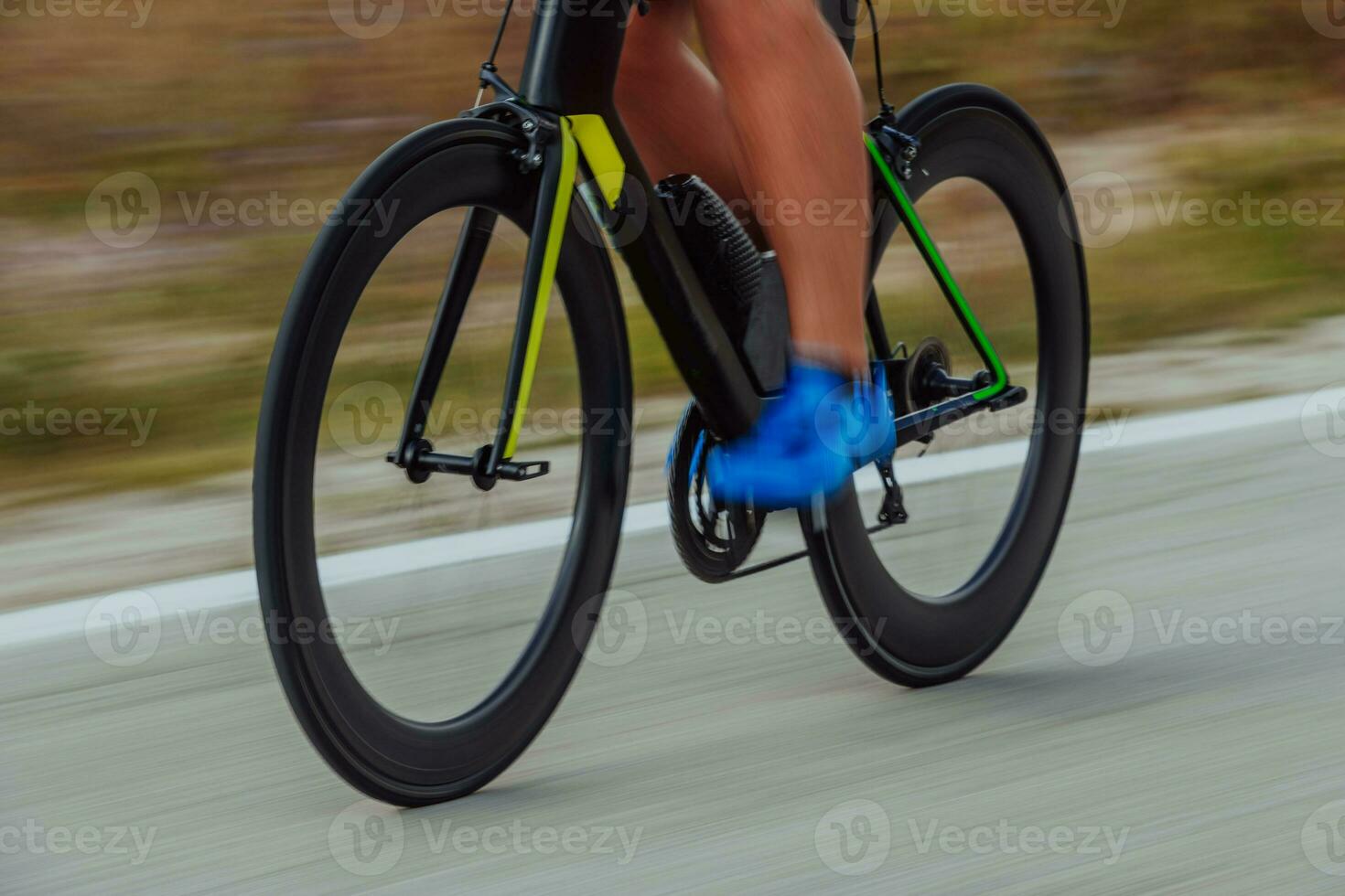 Close up photo of an active triathlete in sportswear and with a protective helmet riding a bicycle. Selective focus