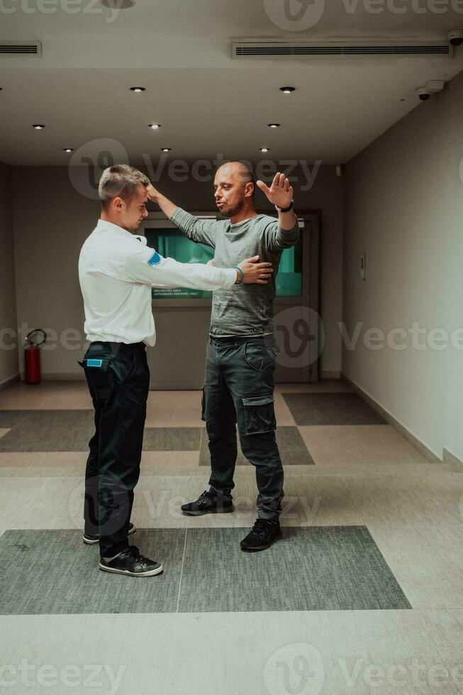 Security guard making body searching procedure on man for finding hidden objects before entering in treasury department photo