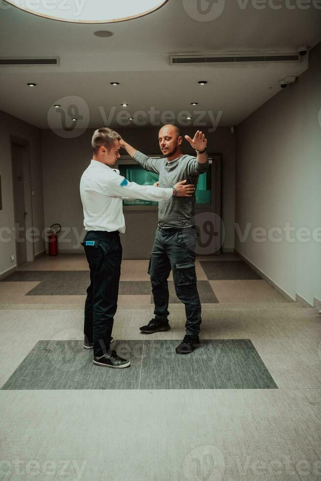 Security guard making body searching procedure on man for finding hidden objects before entering in treasury department photo