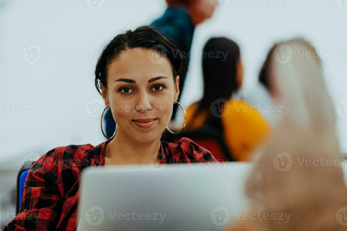 contento mujer trabajando en ordenador portátil en moderno oficina rodeado por amigos foto