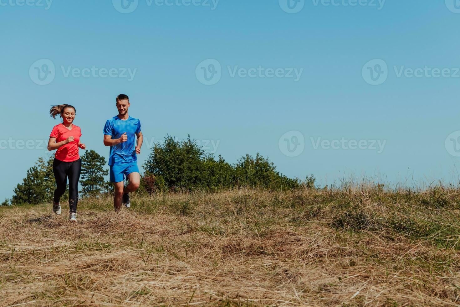 Pareja disfrutando en un sano estilo de vida mientras trotar en un país la carretera mediante el hermosa soleado bosque, ejercicio y aptitud concepto foto