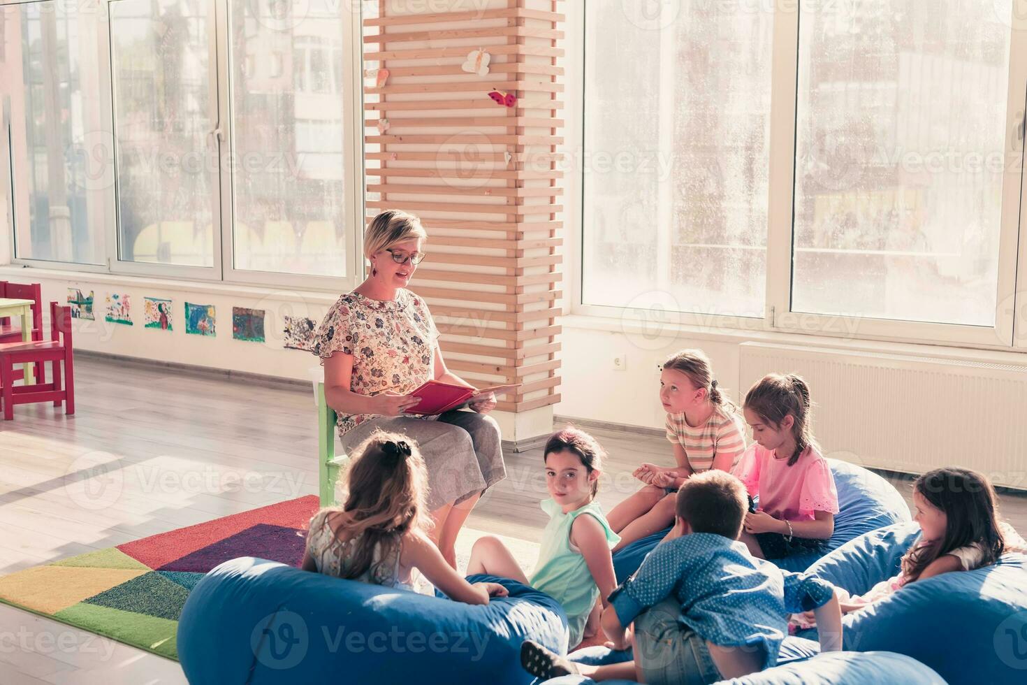 Reading time in elementary school or kindergarten, teacher reading a book to kids in elementary school or kindergaden. Selective focus photo