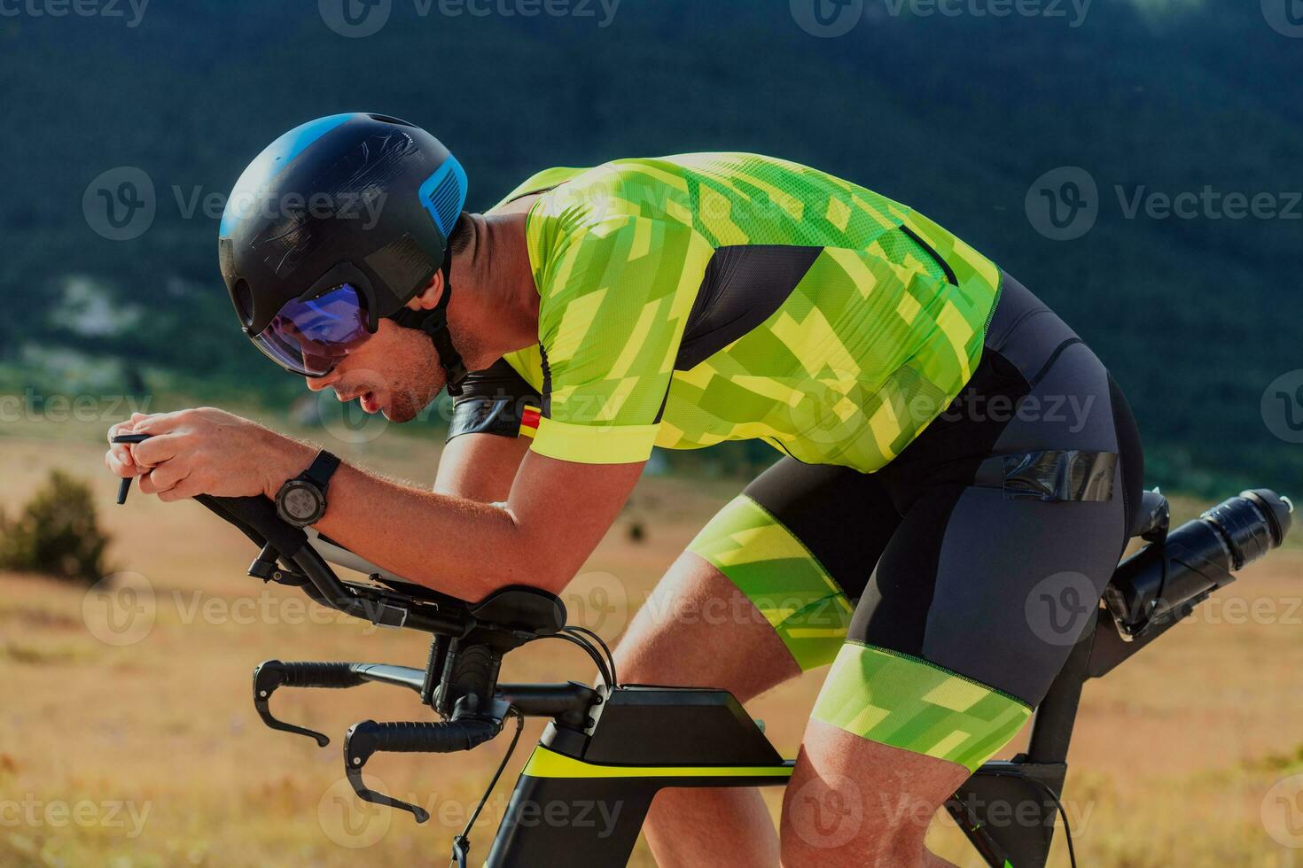 Close up photo of an active triathlete in sportswear and with a protective helmet riding a bicycle. Selective focus