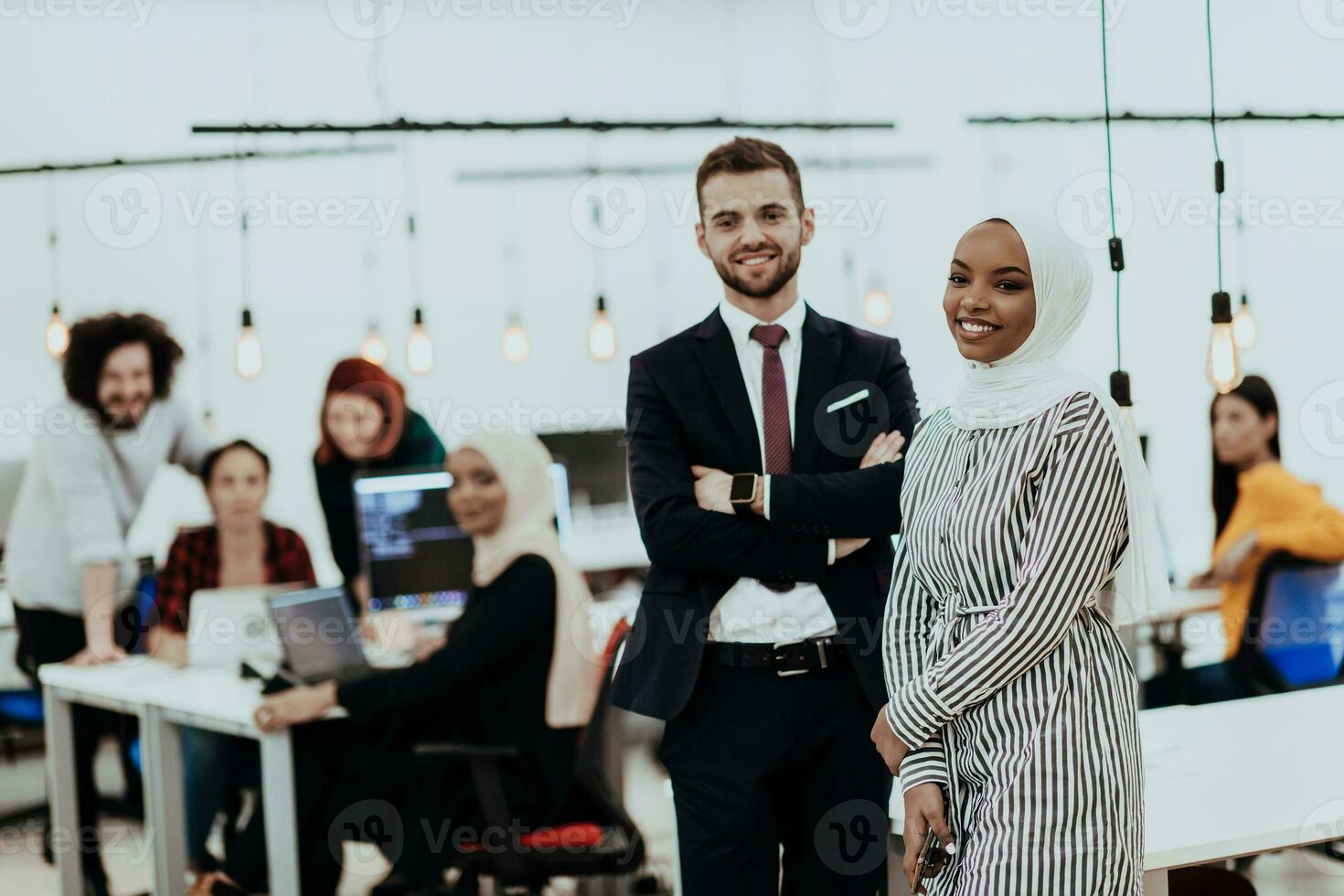 Portrait of a formal businessman and young African American businesswoman posing with their team in a modern startup office. Marketing concept. Multi-ethnic society. photo