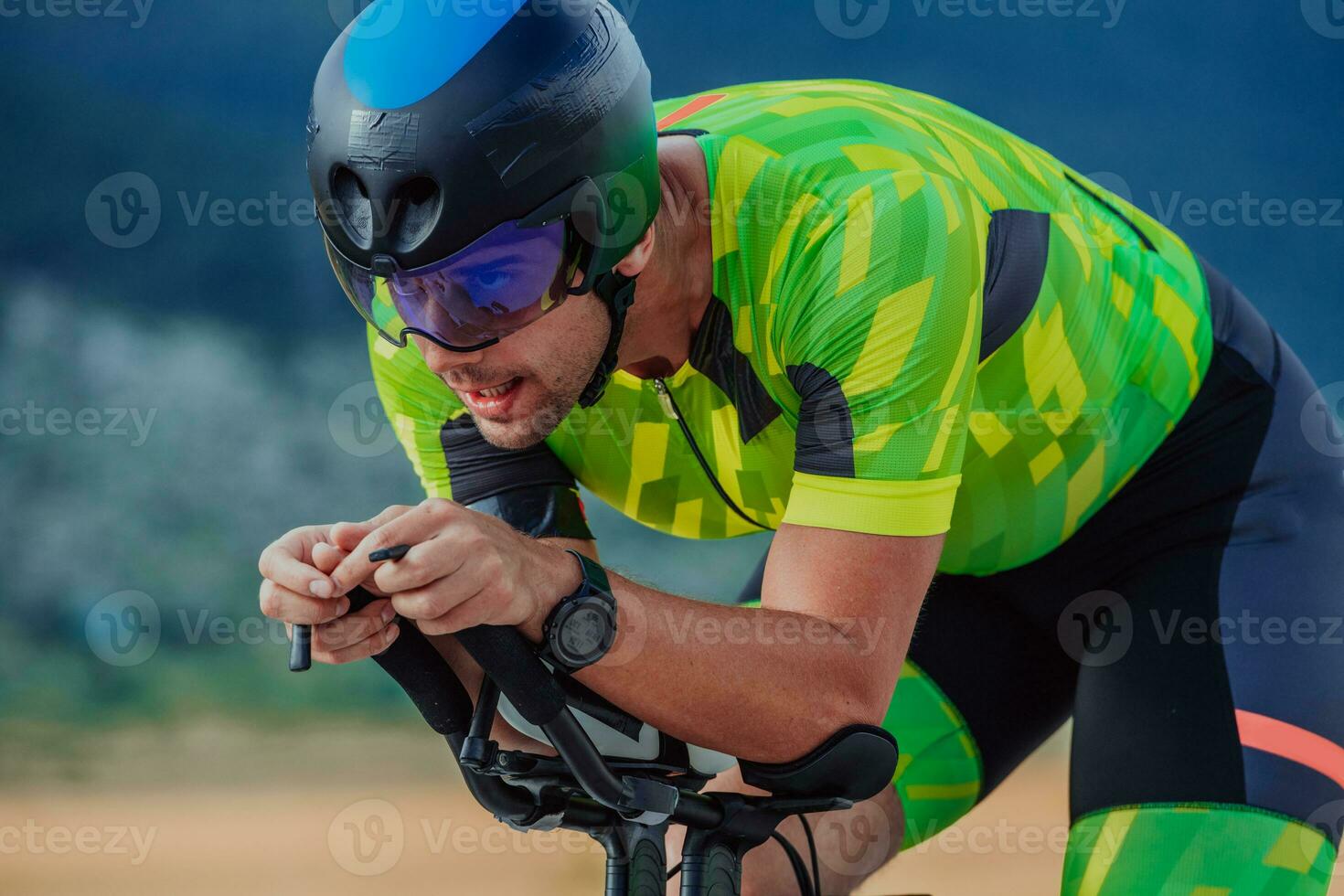 Close up photo of an active triathlete in sportswear and with a protective helmet riding a bicycle. Selective focus