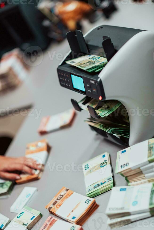 Bank employees using money counting machine while sorting and counting paper banknotes inside bank vault. Large amounts of money in the bank photo