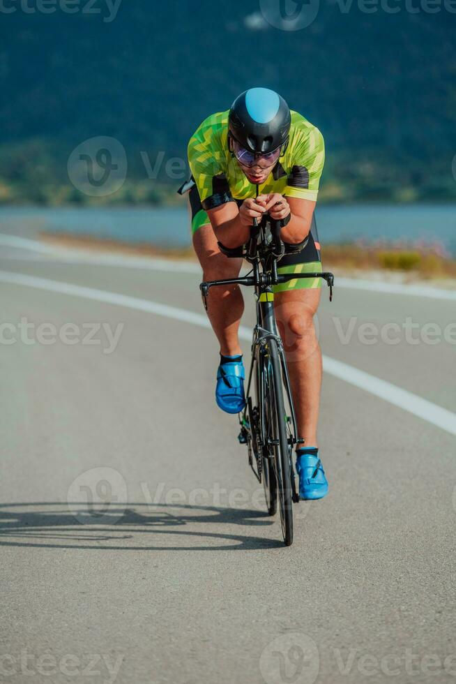 lleno longitud retrato de un activo triatleta en ropa de deporte y con un protector casco montando un bicicleta. selectivo atención foto