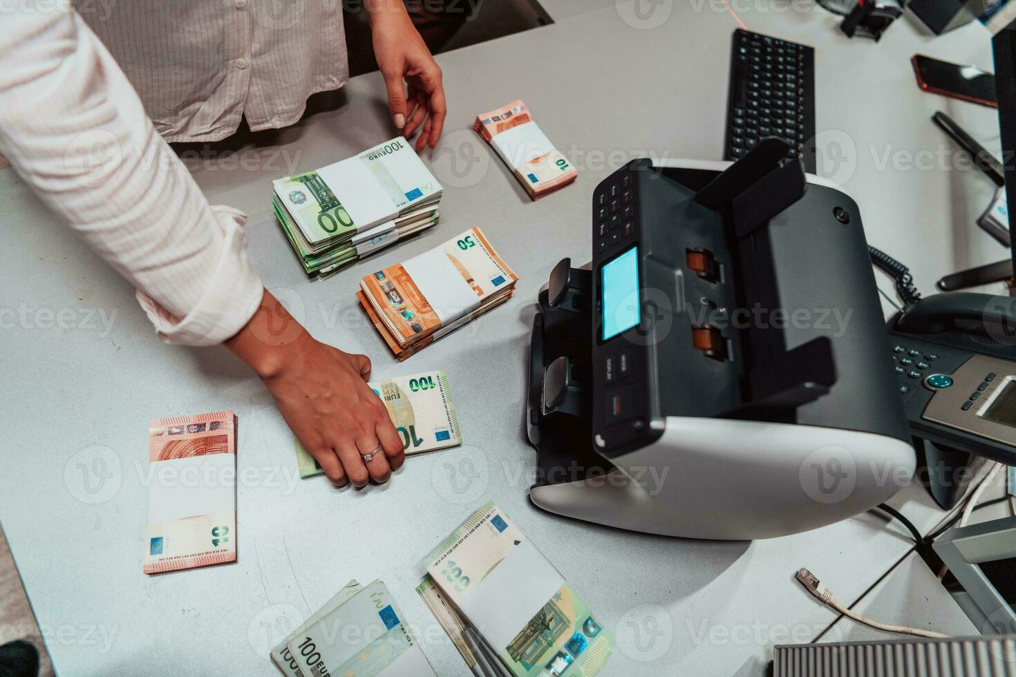 Bank employees using money counting machine while sorting and counting paper banknotes inside bank vault. Large amounts of money in the bank photo
