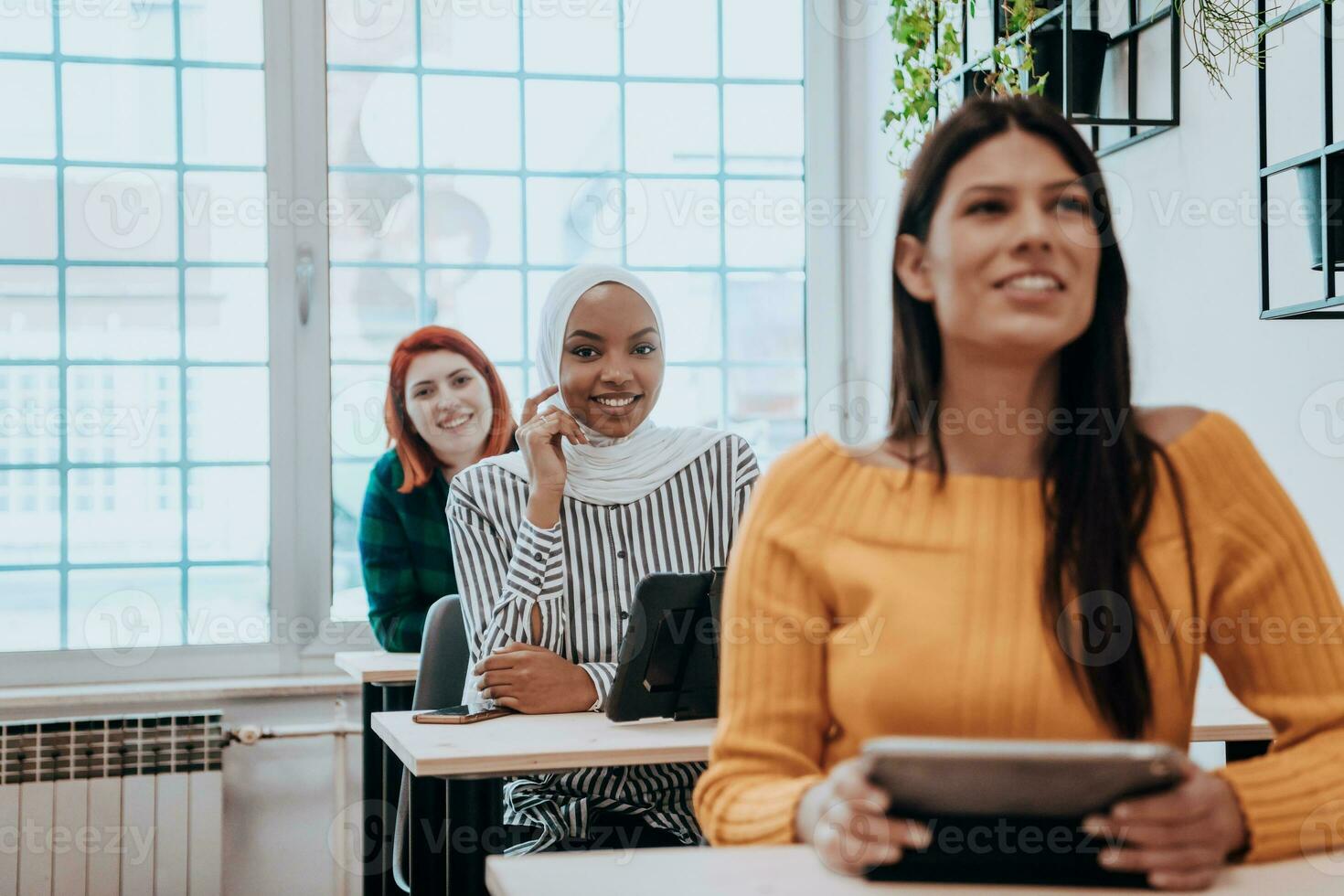 A group of diverse young men and women sit in a modern classroom and listen to a lecture on business training photo