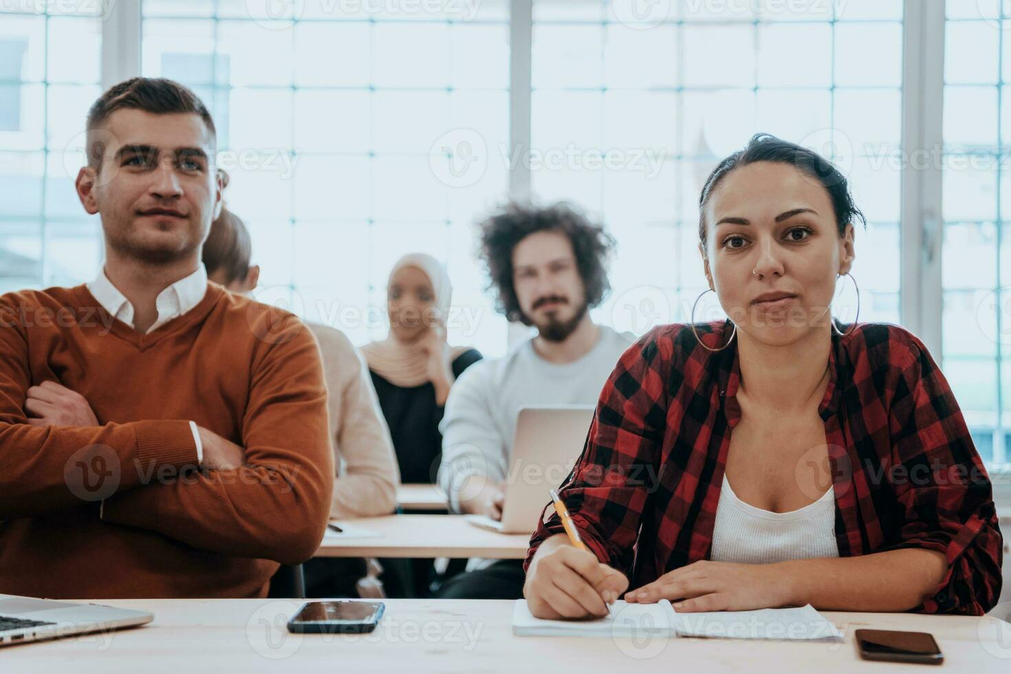 A group of diverse young men and women sit in a modern classroom and listen to a lecture on business training photo