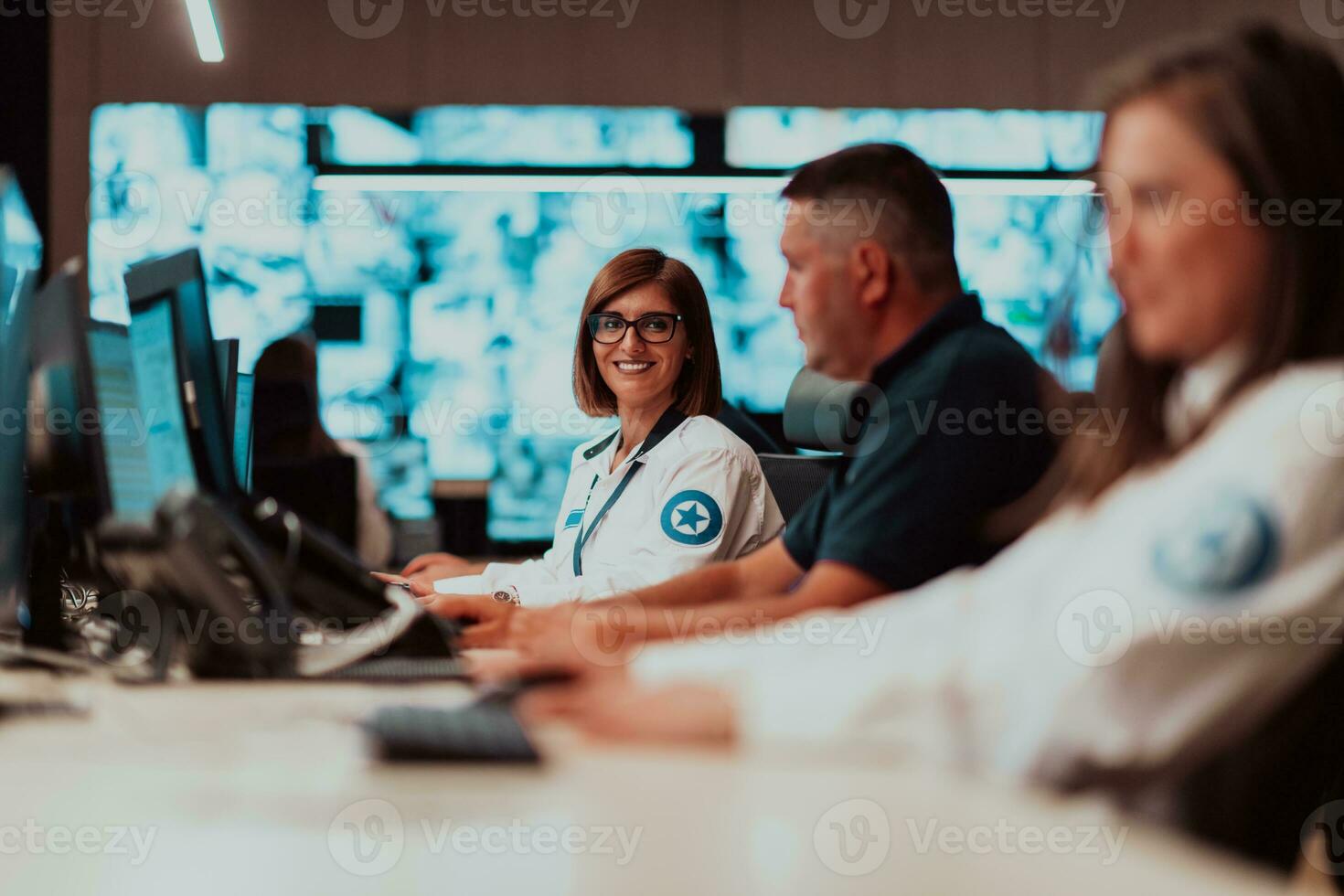 Group of Security data center operators working in a CCTV monitoring room looking on multiple monitors Officers Monitoring Multiple Screens for Suspicious Activities Team working on the System Contr photo