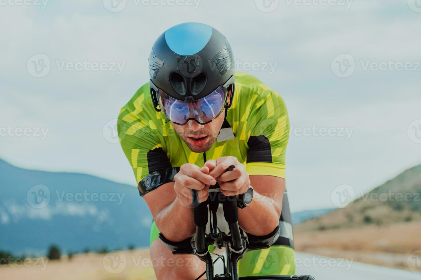 cerca arriba foto de un activo triatleta en ropa de deporte y con un protector casco montando un bicicleta. selectivo atención