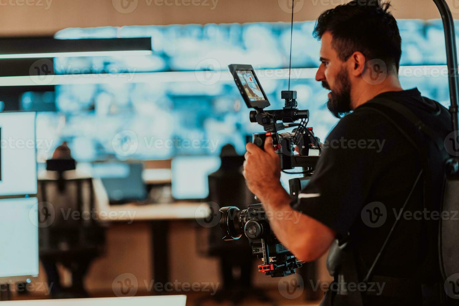 Professional videographer with gimball video slr recording video of Security data center operators while working in a CCTV monitoring room looking on multiple monitors Team working on the System Con photo