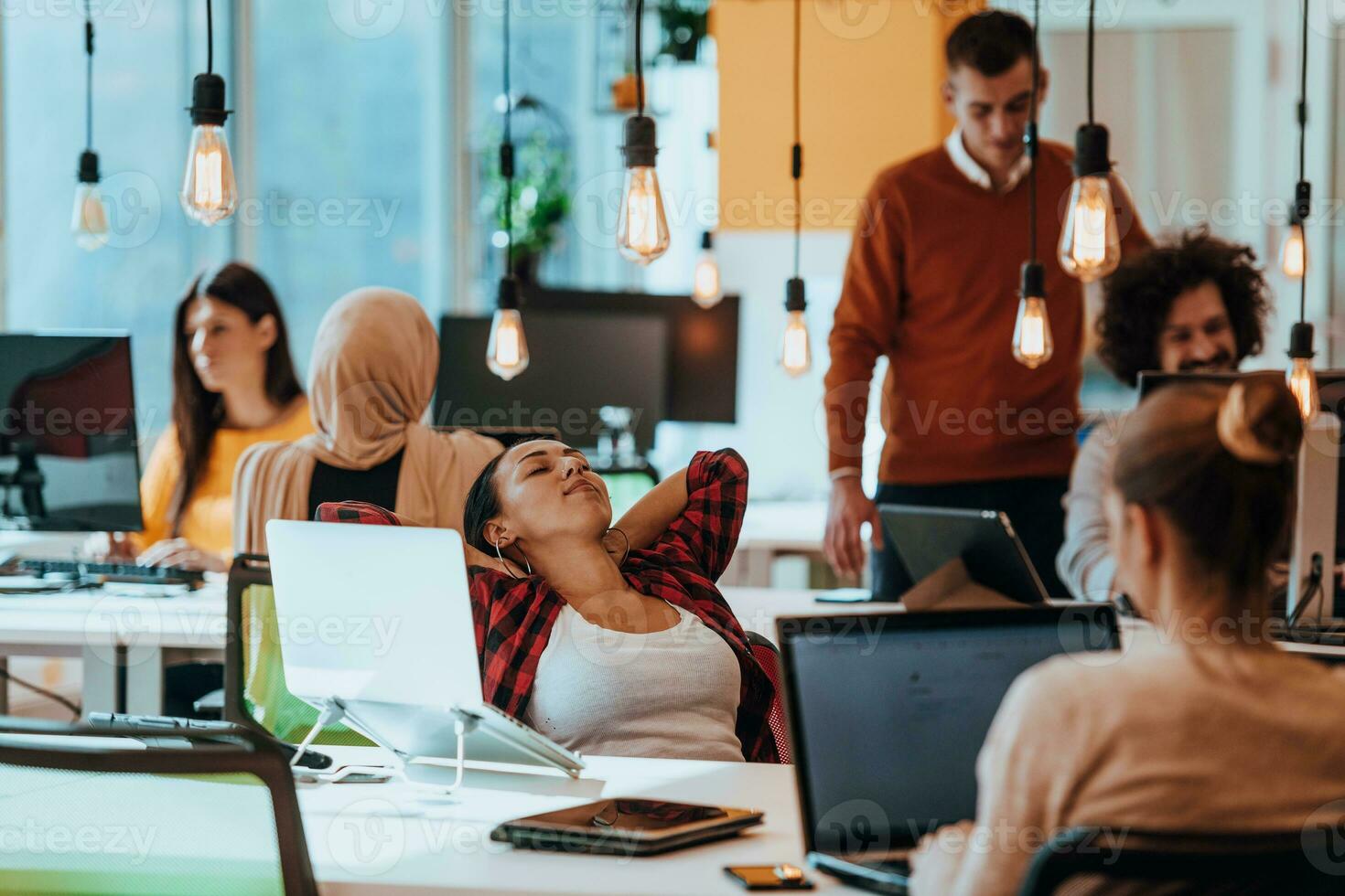 Group of multi-ethnic colleagues working on desktop computers, laptop and sharing their ideas in a modern office space.Young influencers work on online marketing projects. photo