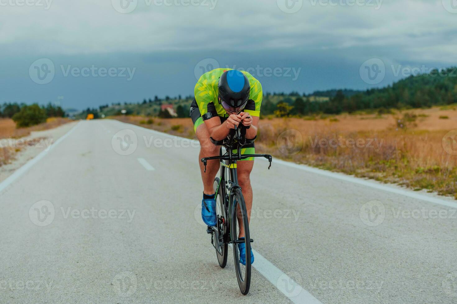 lleno longitud retrato de un activo triatleta en ropa de deporte y con un protector casco montando un bicicleta. selectivo atención foto