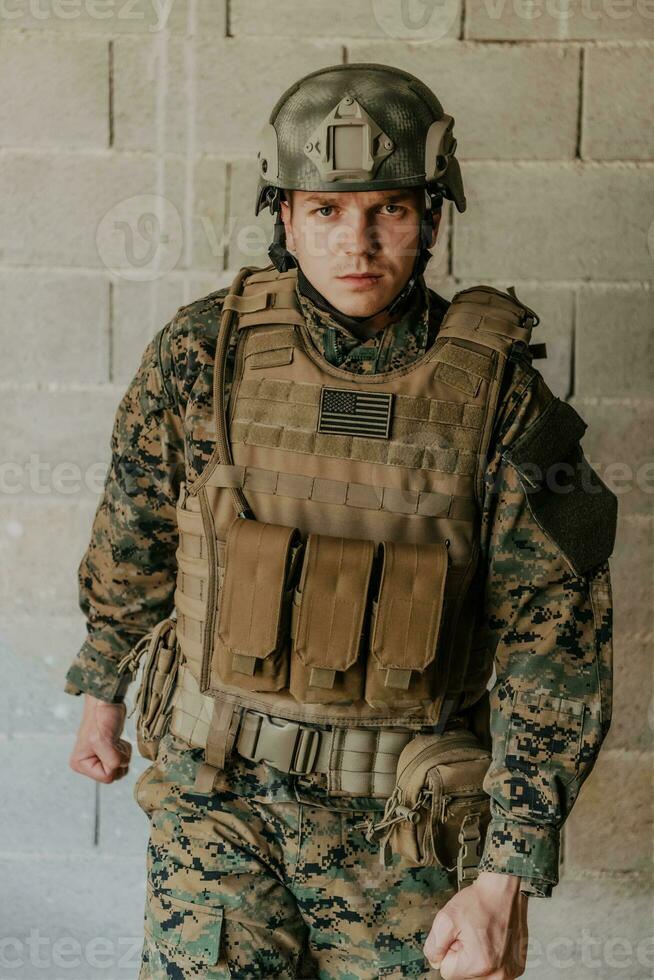 A soldier in uniform stands in front of a stone wall in full war gear preparing for battle photo