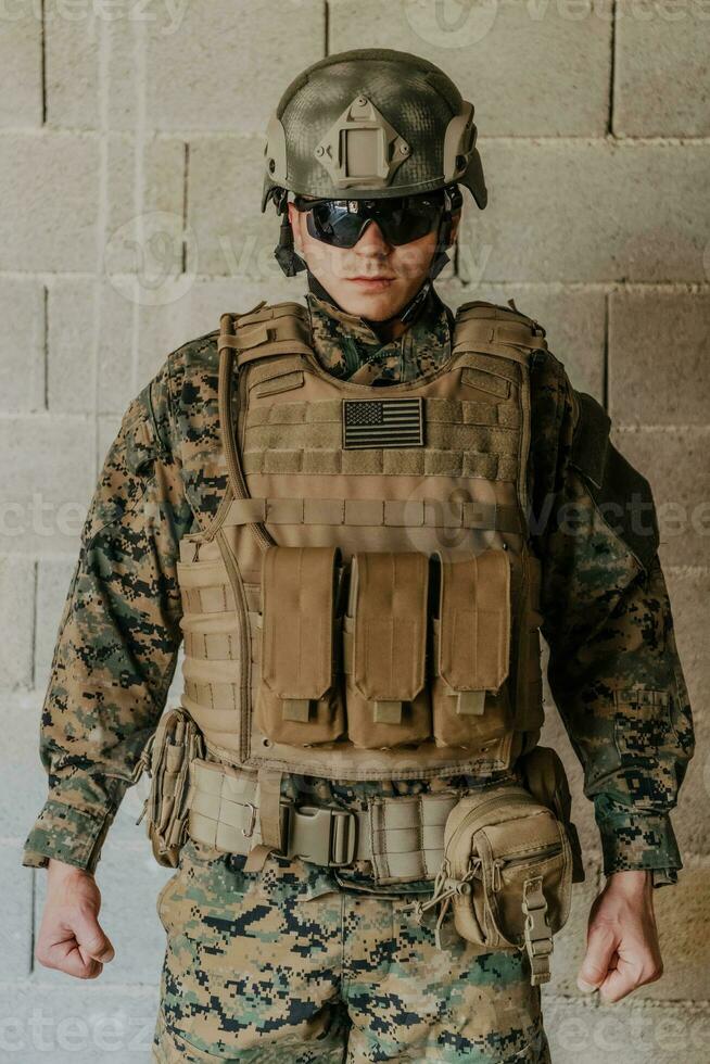 A soldier in uniform stands in front of a stone wall in full war gear preparing for battle photo
