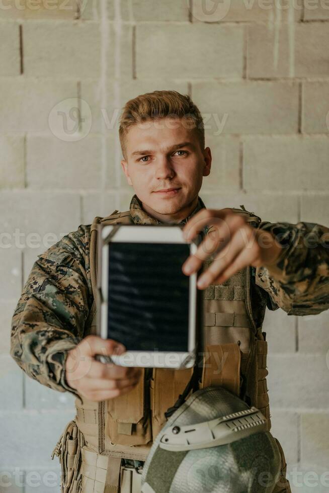 Soldier using tablet computer against old brick wall photo