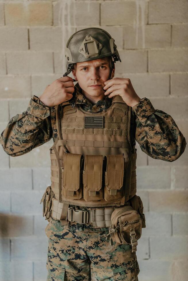 A soldier in uniform stands in front of a stone wall in full war gear preparing for battle photo