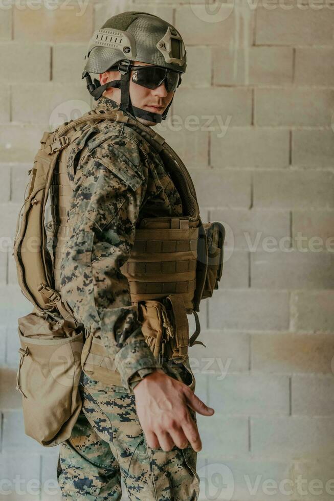 A soldier in uniform stands in front of a stone wall in full war gear preparing for battle photo