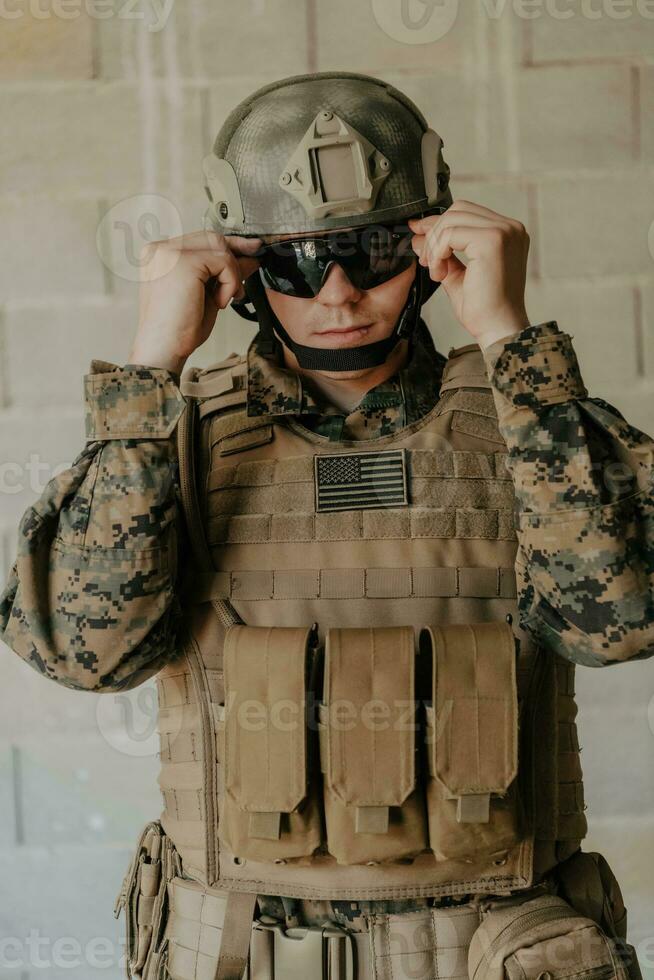 A soldier in uniform stands in front of a stone wall in full war gear preparing for battle photo