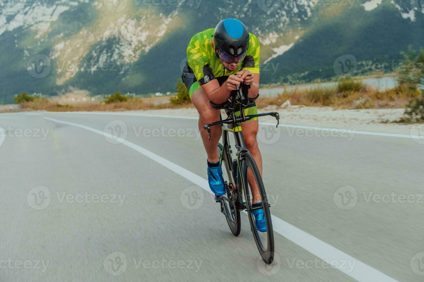 Full length portrait of an active triathlete in sportswear and with a protective helmet riding a bicycle. Selective focus photo