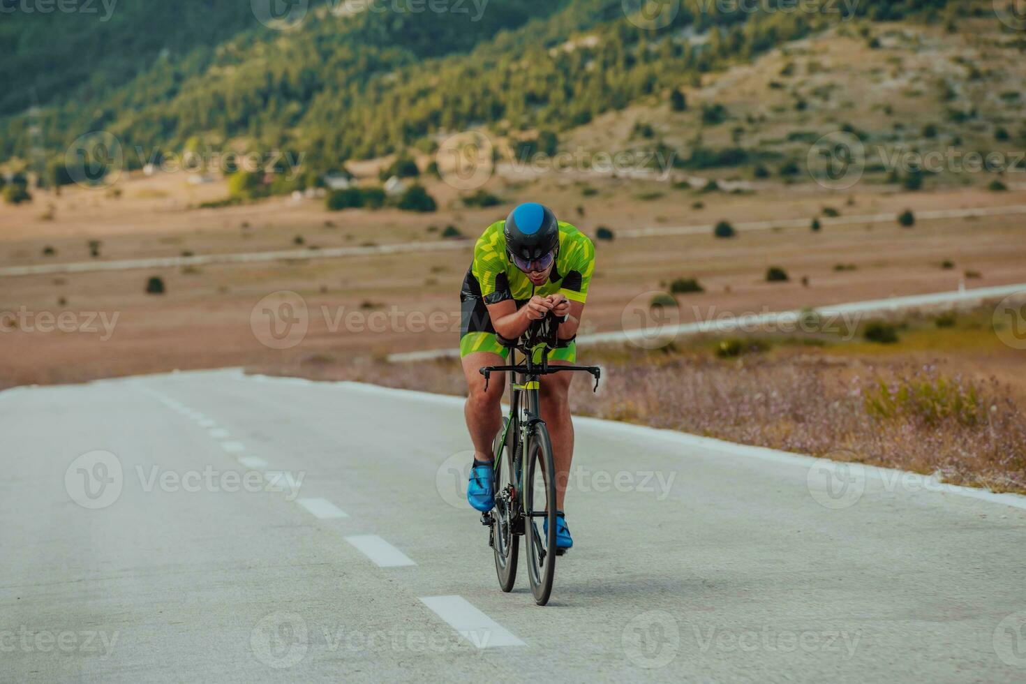 Full length portrait of an active triathlete in sportswear and with a protective helmet riding a bicycle. Selective focus photo