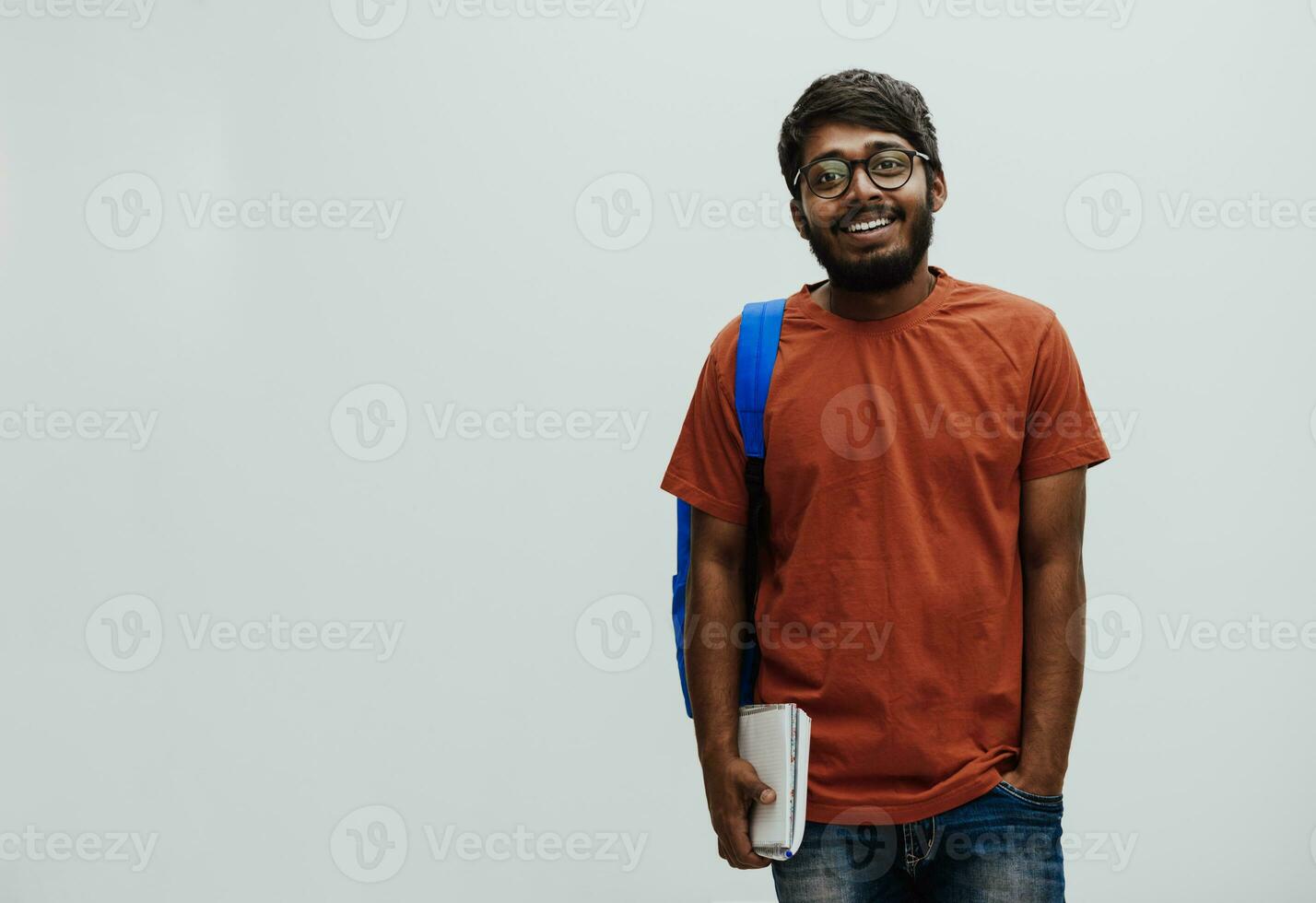 Indian student with blue backpack, glasses and notebook posing on gray background. The concept of education and schooling. Time to go back to school photo