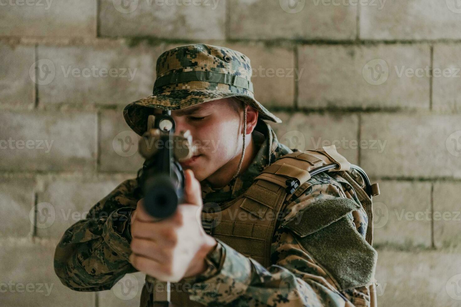 A soldier in uniform stands in front of a stone wall in full war gear preparing for battle photo