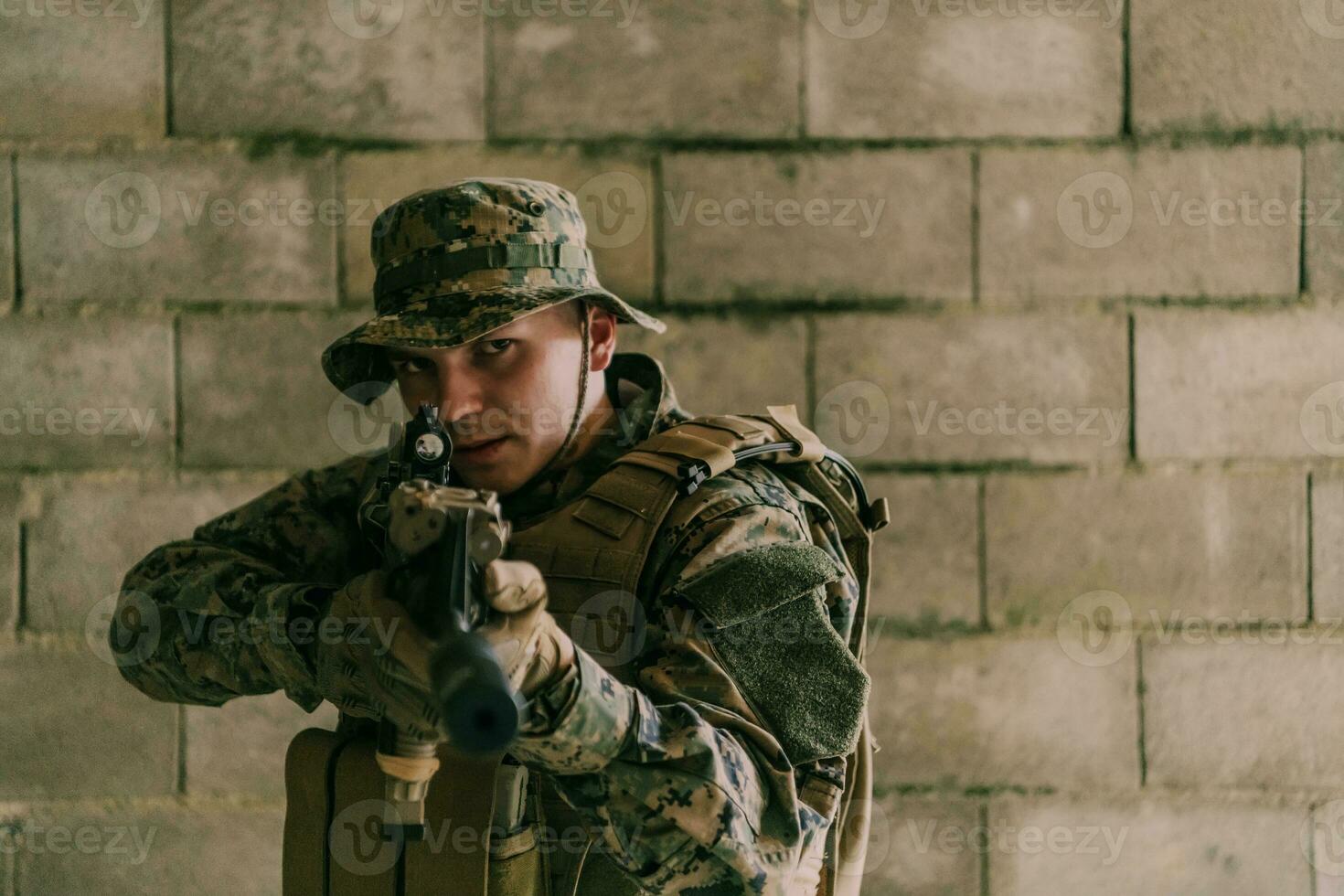 A soldier in uniform stands in front of a stone wall in full war gear preparing for battle photo