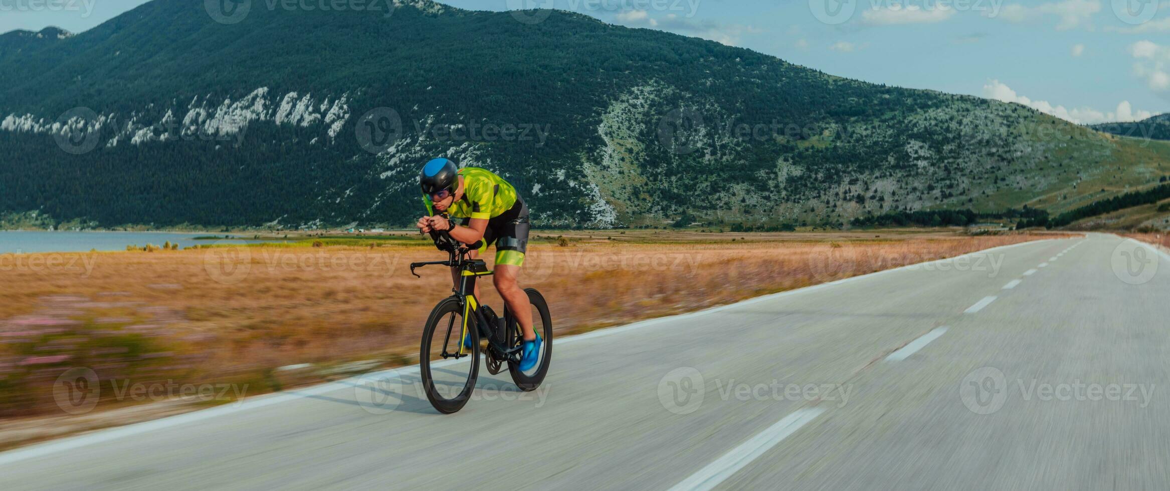 Full length portrait of an active triathlete in sportswear and with a protective helmet riding a bicycle. Selective focus photo