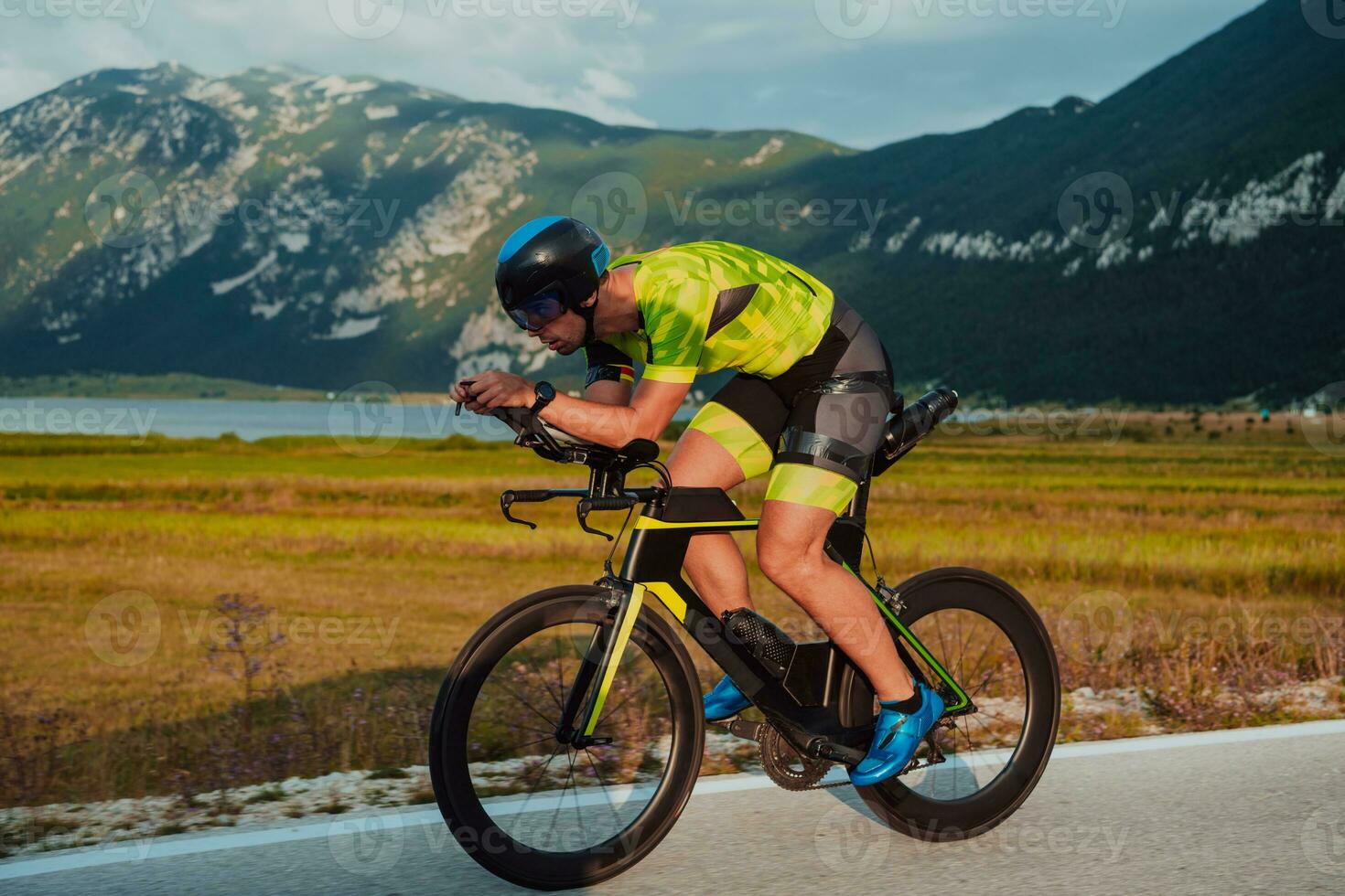 Full length portrait of an active triathlete in sportswear and with a protective helmet riding a bicycle. Selective focus photo