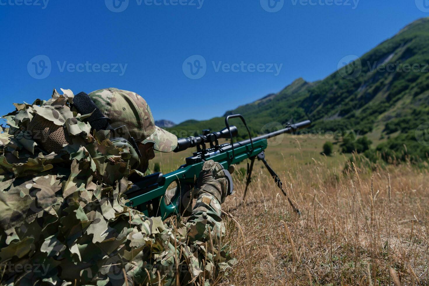 Army soldier holding sniper rifle with scope and aiming in forest. War, army, technology and people concept photo