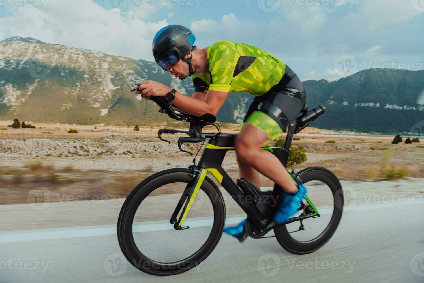 Full length portrait of an active triathlete in sportswear and with a protective helmet riding a bicycle. Selective focus photo