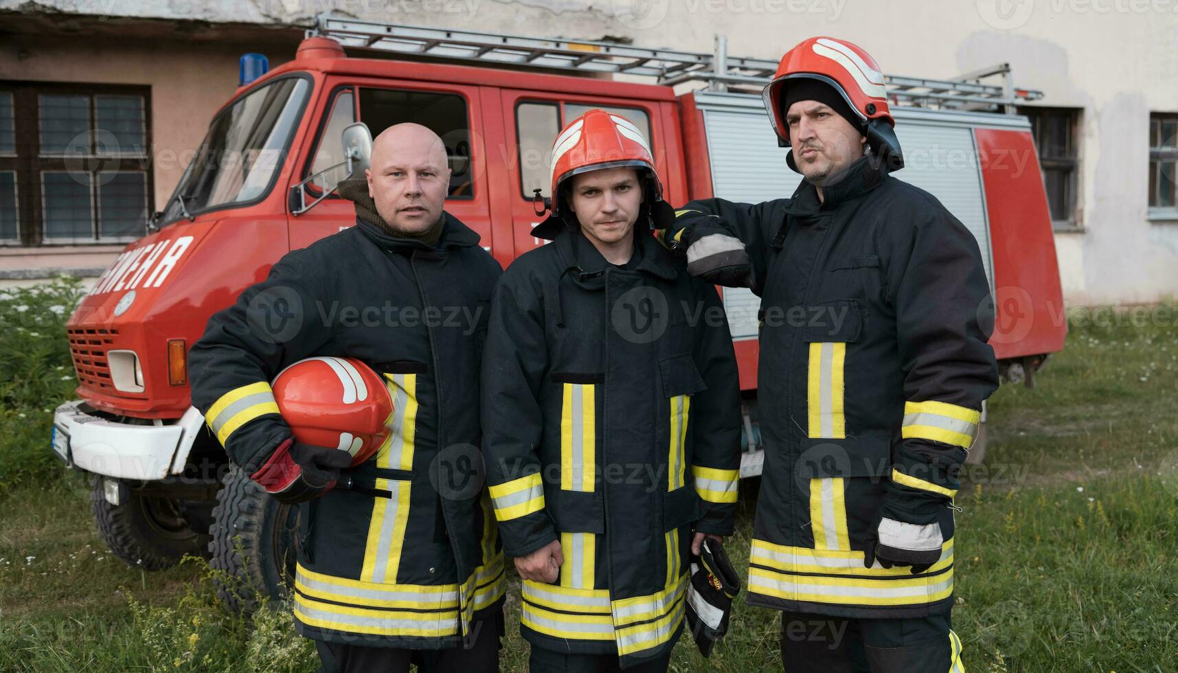 Group of fire fighters standing confident after a well done rescue operation. Firemen ready for emergency service. photo