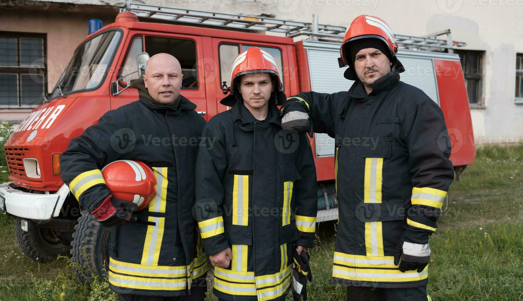 Group of fire fighters standing confident after a well done rescue operation. Firemen ready for emergency service. photo