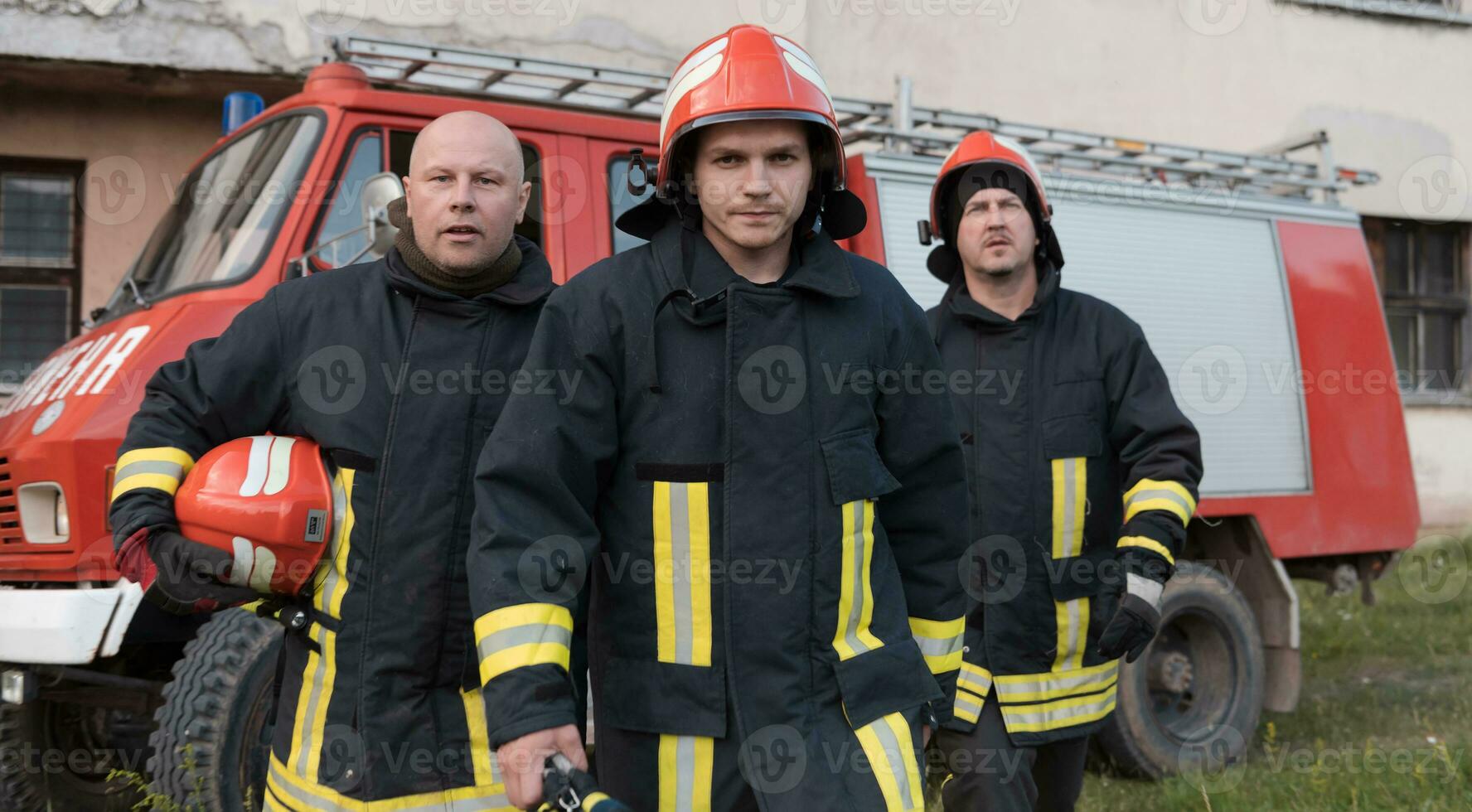 Group of fire fighters standing confident after a well done rescue operation. Firemen ready for emergency service. photo