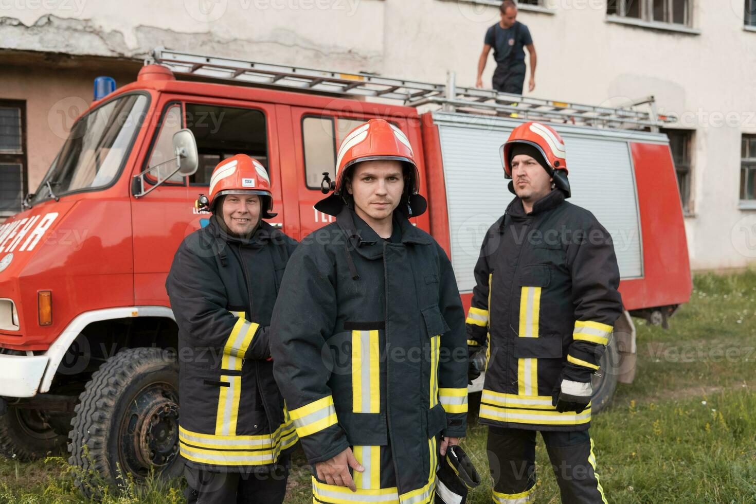 Group of fire fighters standing confident after a well done rescue operation. Firemen ready for emergency service. photo