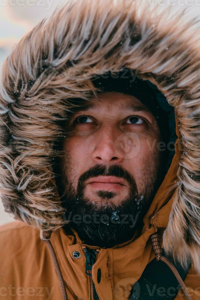 Headshot photo of a man in a cold snowy area wearing a thick brown winter jacket and gloves. Life in cold regions of the country.