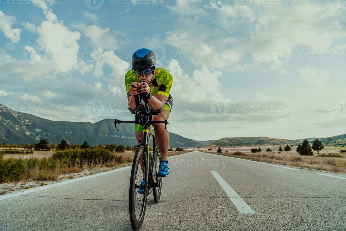 lleno longitud retrato de un activo triatleta en ropa de deporte y con un protector casco montando un bicicleta. selectivo atención foto