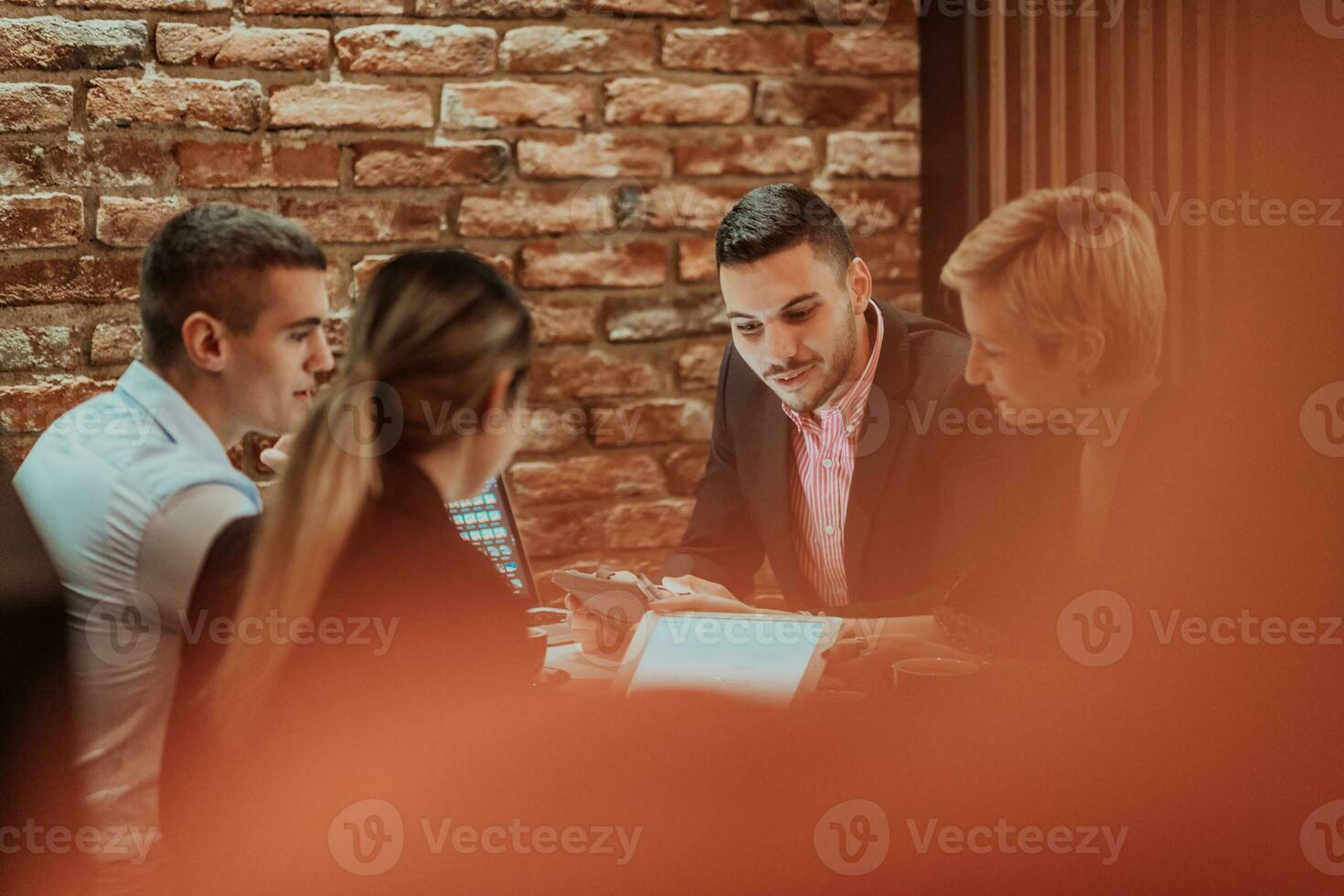 Happy businesspeople smiling cheerfully during a meeting in a coffee shop. Group of successful business professionals working as a team in a multicultural workplace. photo