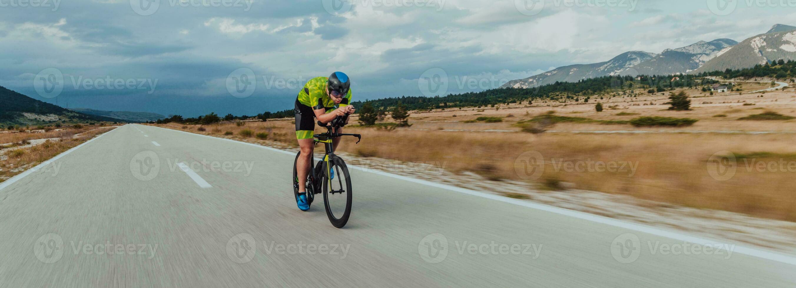 Full length portrait of an active triathlete in sportswear and with a protective helmet riding a bicycle. Selective focus photo