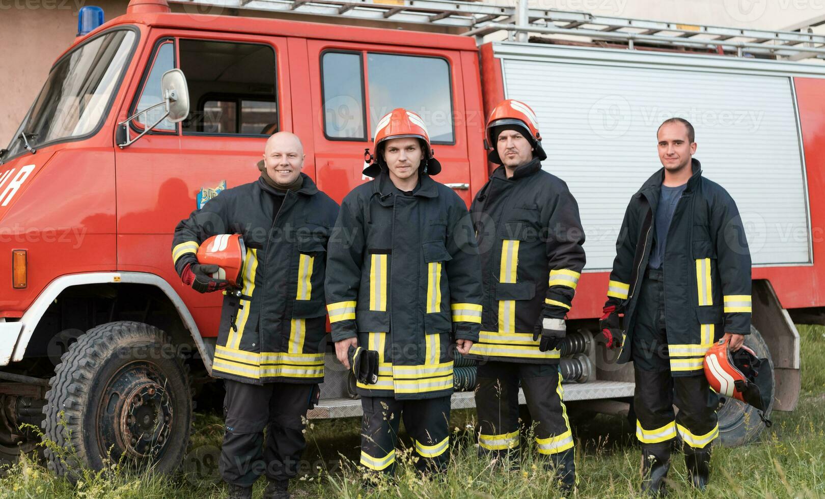 Group of fire fighters standing confident after a well done rescue operation. Firemen ready for emergency service. photo
