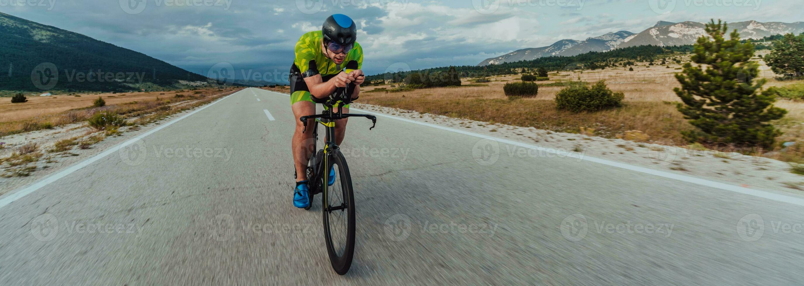 Full length portrait of an active triathlete in sportswear and with a protective helmet riding a bicycle. Selective focus photo