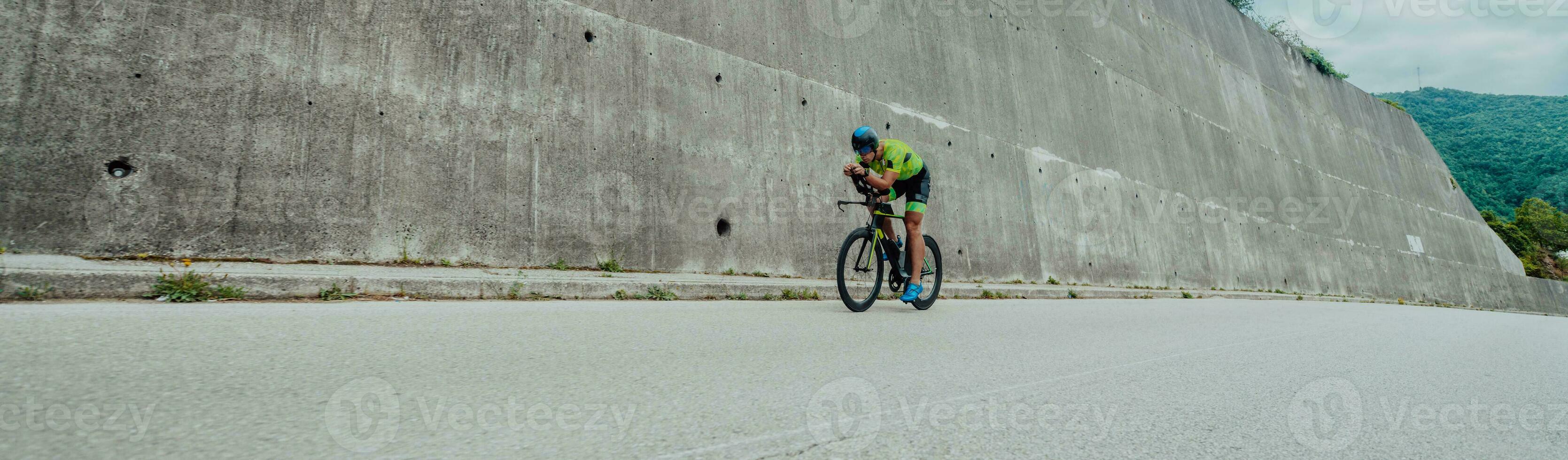 Full length portrait of an active triathlete in sportswear and with a protective helmet riding a bicycle. Selective focus photo