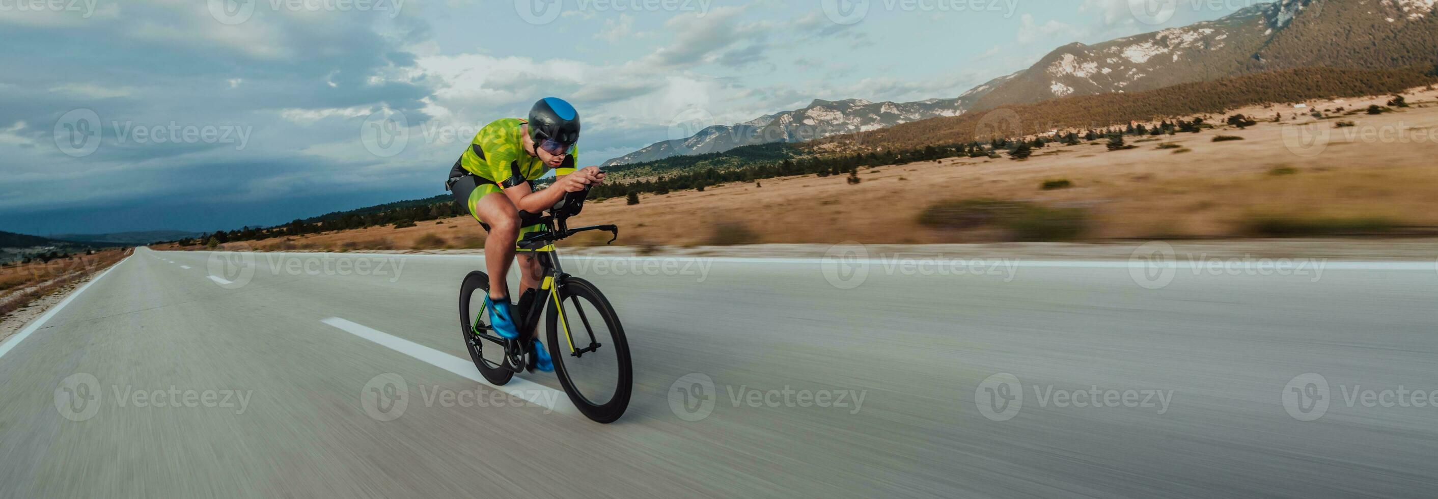 Full length portrait of an active triathlete in sportswear and with a protective helmet riding a bicycle. Selective focus photo