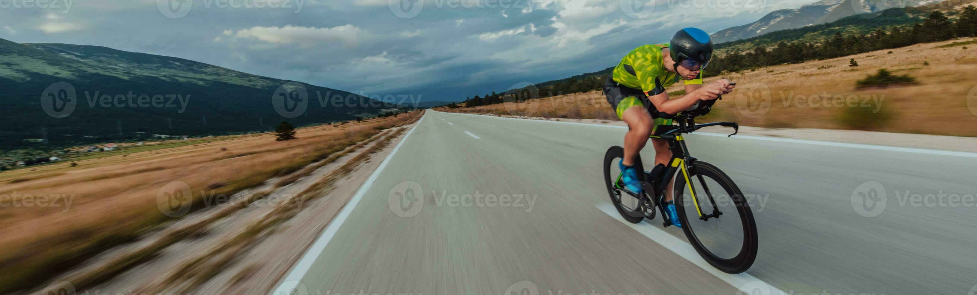 Full length portrait of an active triathlete in sportswear and with a protective helmet riding a bicycle. Selective focus photo